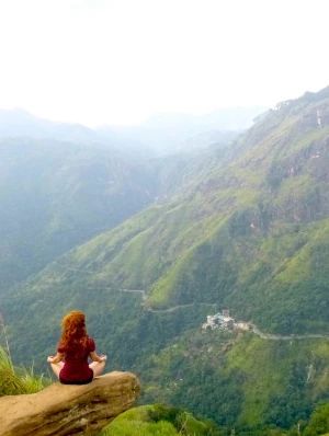 a girl at the edge of little adams peak ella. ella rock in the background